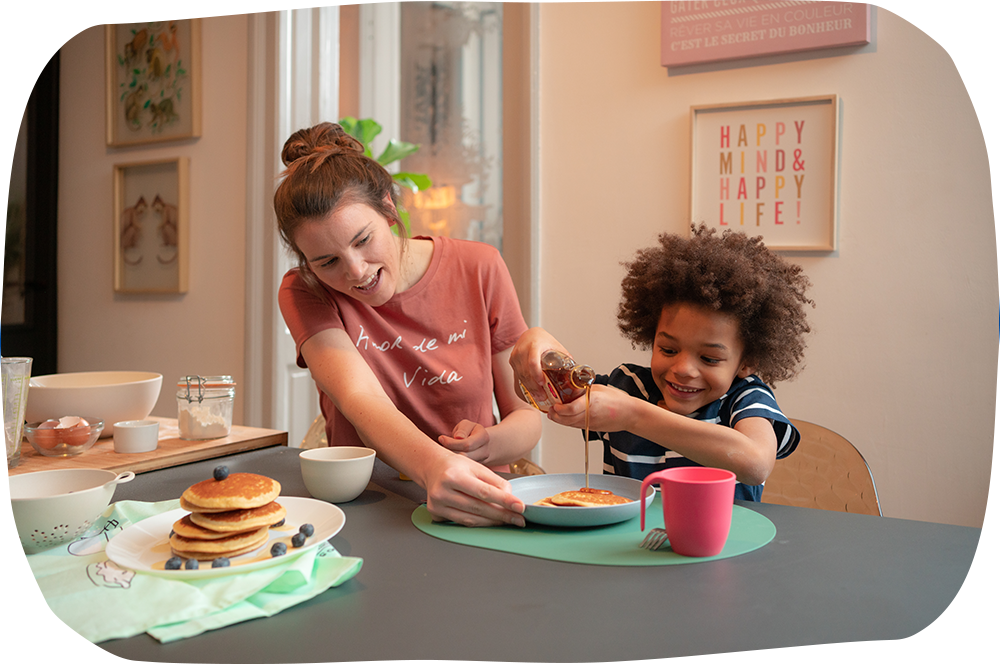 une nounou prépare des pancakes avec un enfant