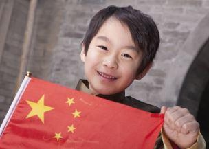Enfant chinois souriant portant le drapeau de la Chine